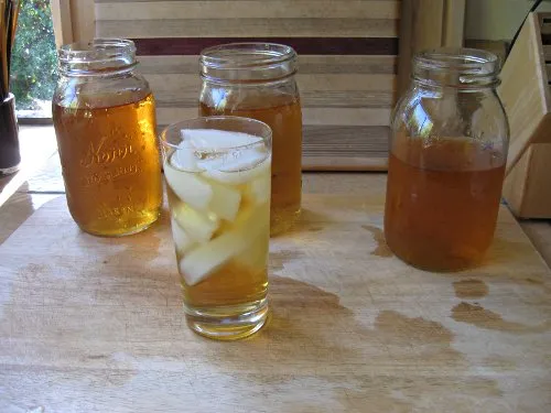 The strained tea in jars with a serving glass in the foreground